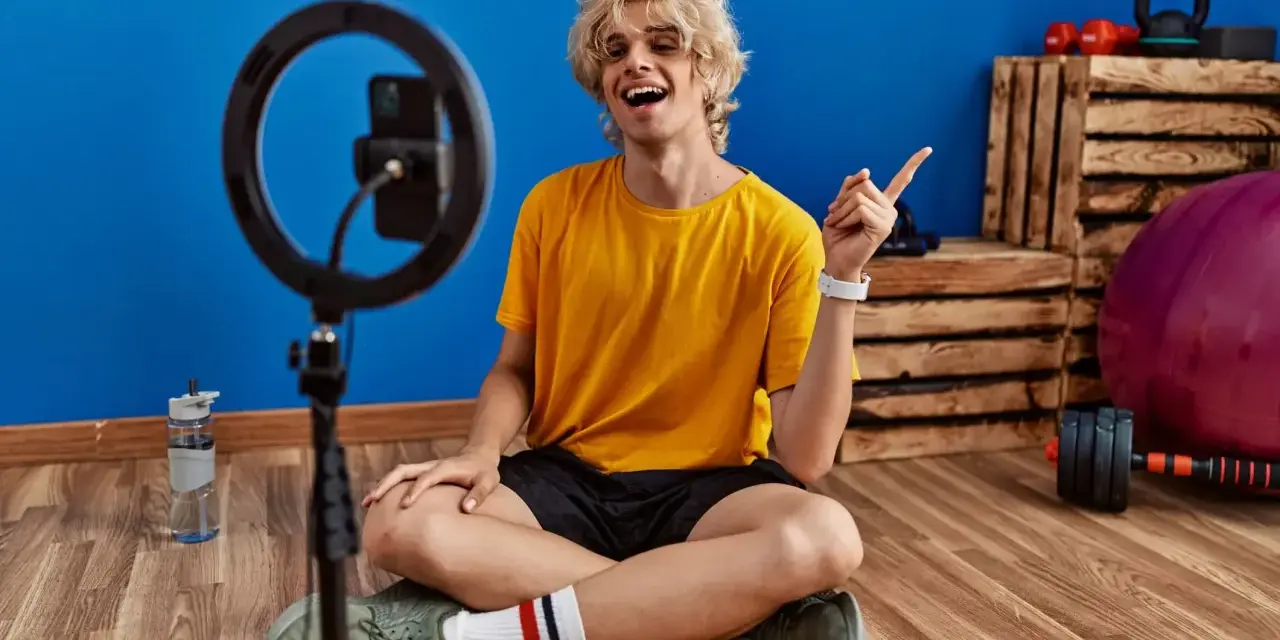 Joven influencer de fitness sonríe y señala, listo para grabar sus acciones con influencers.