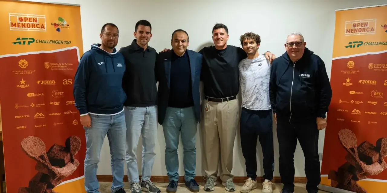 Roberto Carballes Baena posa con otros hombres frente a un cartel del Open Menorca ATP Challenger 100.