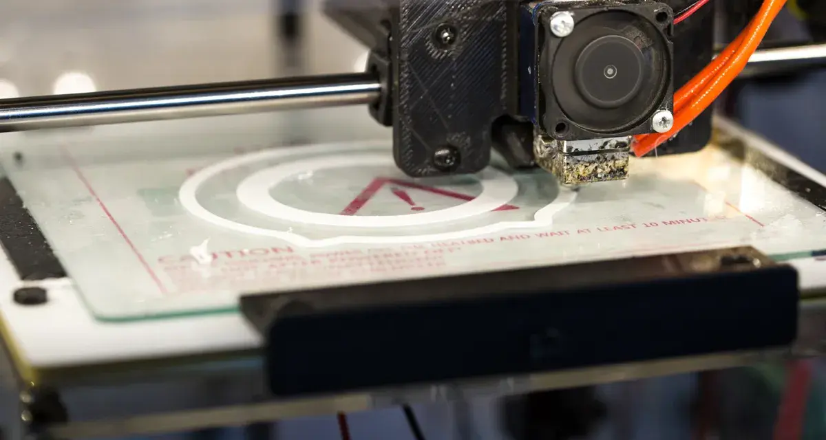 Głowica drukarki 3D tworzy biały okrąg na szklanej platformie. To część projektu drukarki 3d.