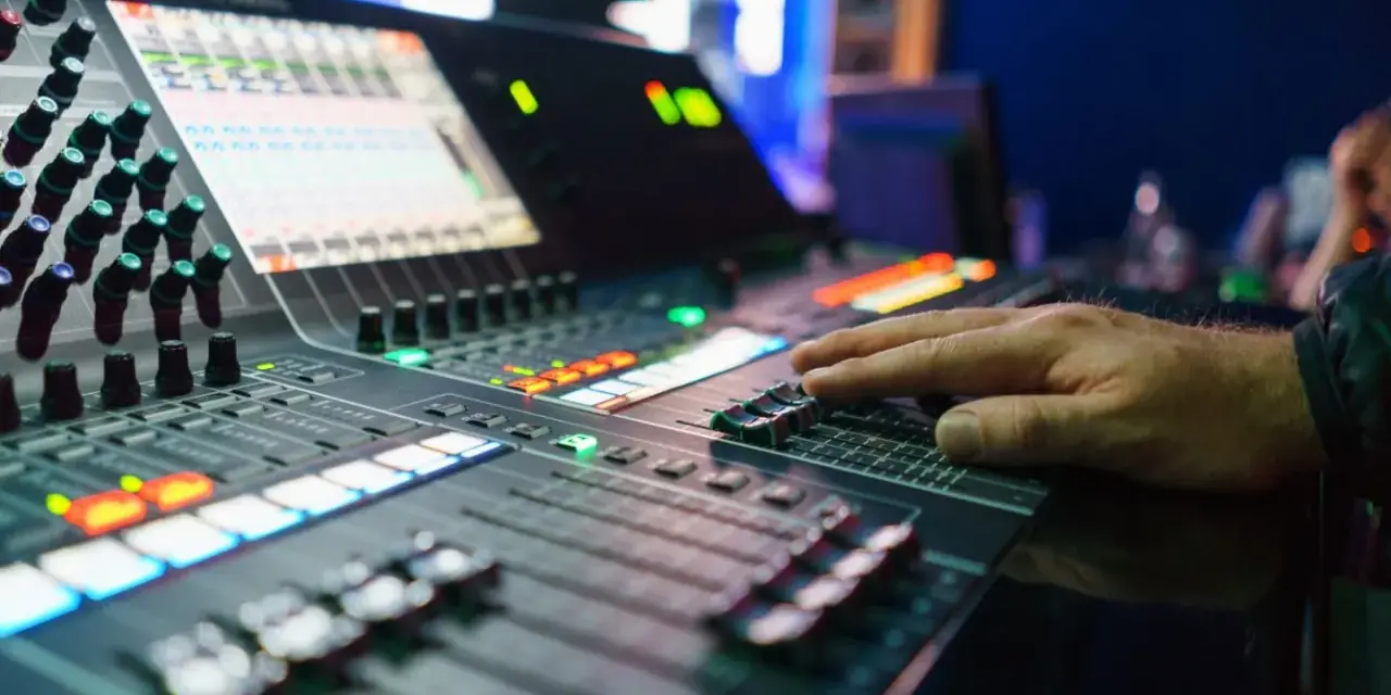 Hand bedient Mischpult für professionelles music management. Lichter und Regler zeigen die komplexe Steuerung.