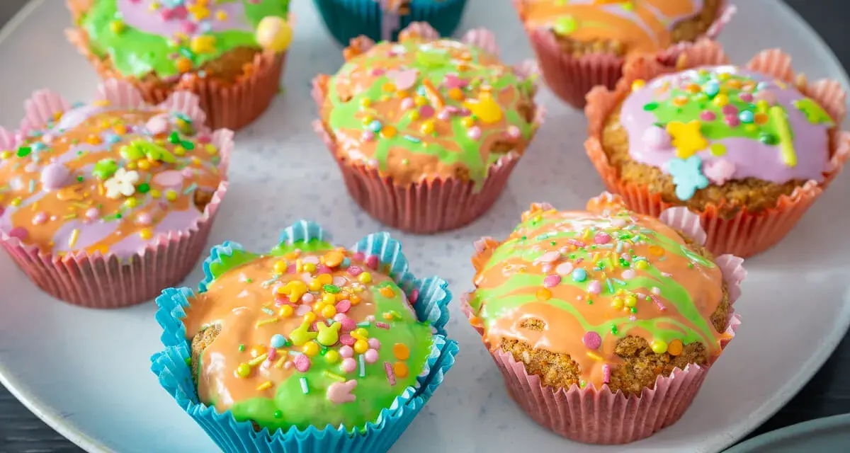 Bunte Karottenmuffins mit Zuckerguss und Streuseln, perfekt für ein Frühlingsfest. Dieses Karottenmuffins Rezept ist ein Hit!
