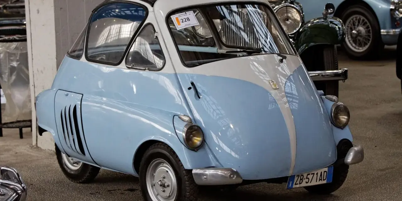 Urocze, błękitno-białe BMW Isetta z lat 50. z charakterystycznymi drzwiami z przodu, gotowe na przejażdżkę po mieście.