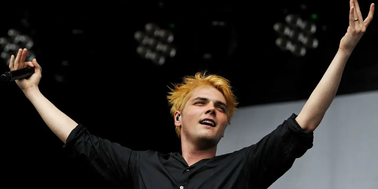 Gerard Way, Sänger des Musikgenres mit E, mit blonden Haaren und erhobenen Armen auf der Bühne.