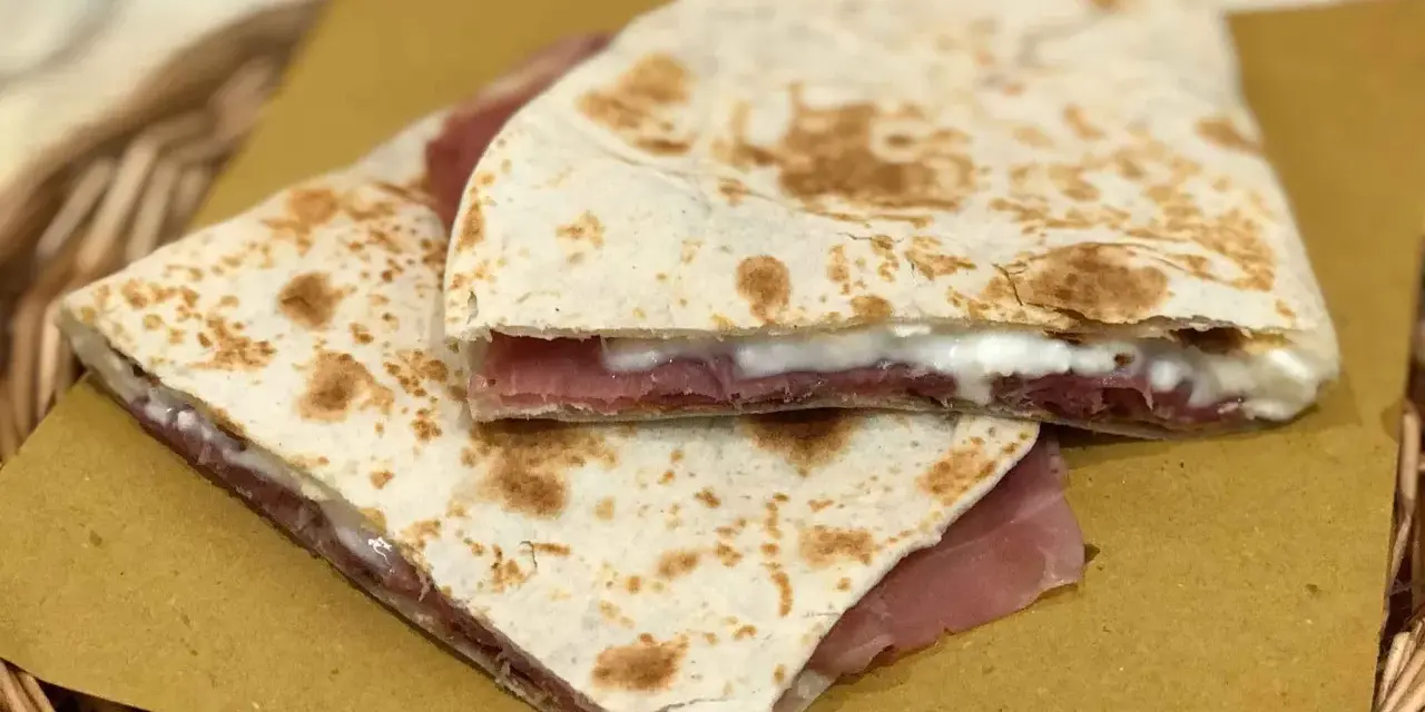 Piadine ripiegate con prosciutto e formaggio cremoso, semplici ingredienti piadina che creano un sapore delizioso.