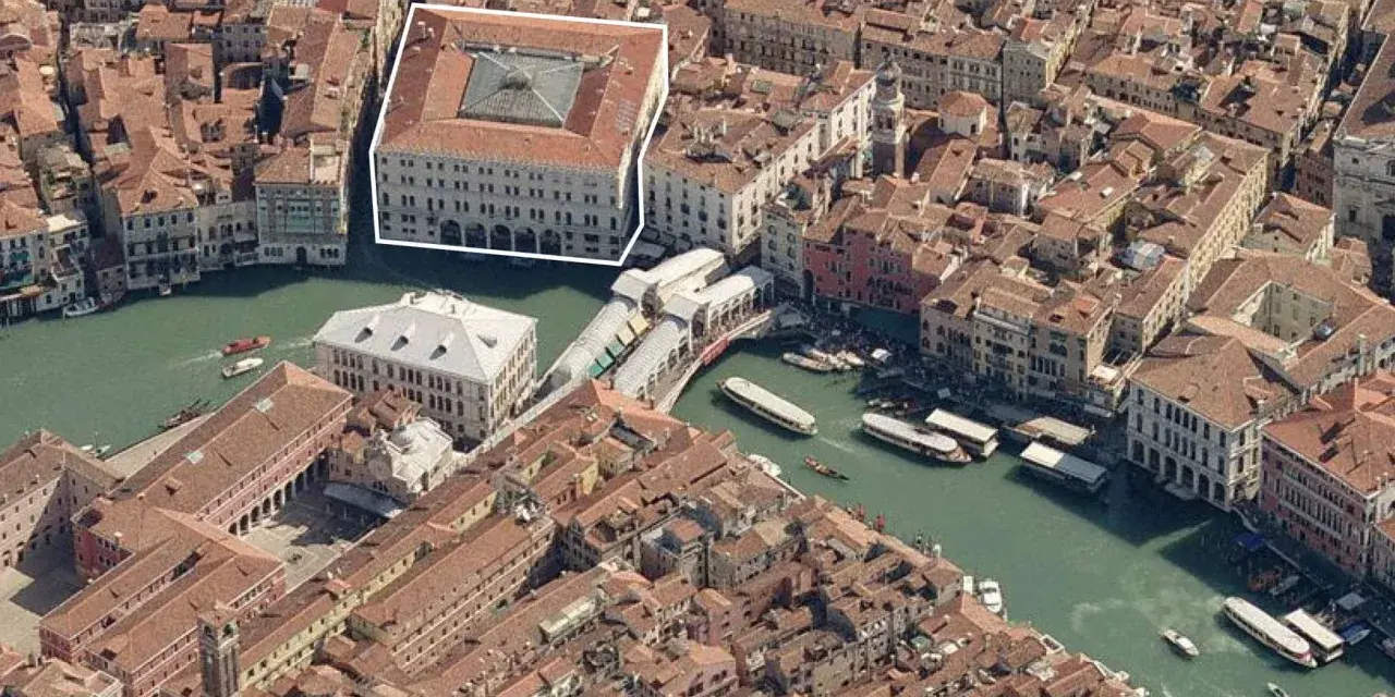 Vista aerea di Venezia, evidenziato il Fondaco dei Tedeschi, un imponente edificio storico affacciato sul Canal Grande, vicino al Ponte di Rialto.