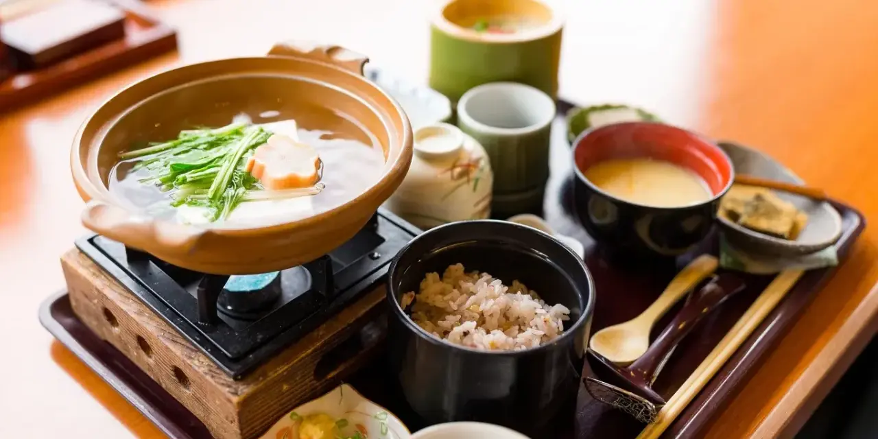 Japońskie śniadanie: gorący bulion z warzywami i tofu, ryż, zupa miso i dodatki.