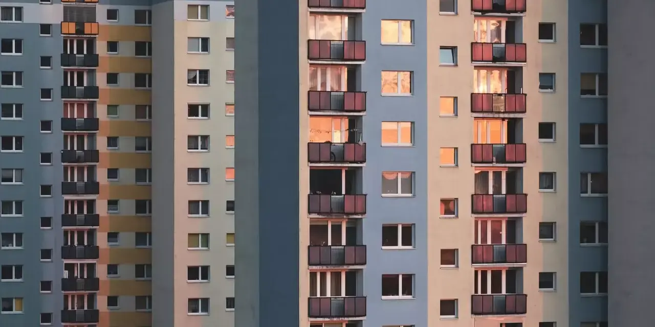 Widok na fasadę wielopiętrowych bloków mieszkalnych z balkonami i oknami.