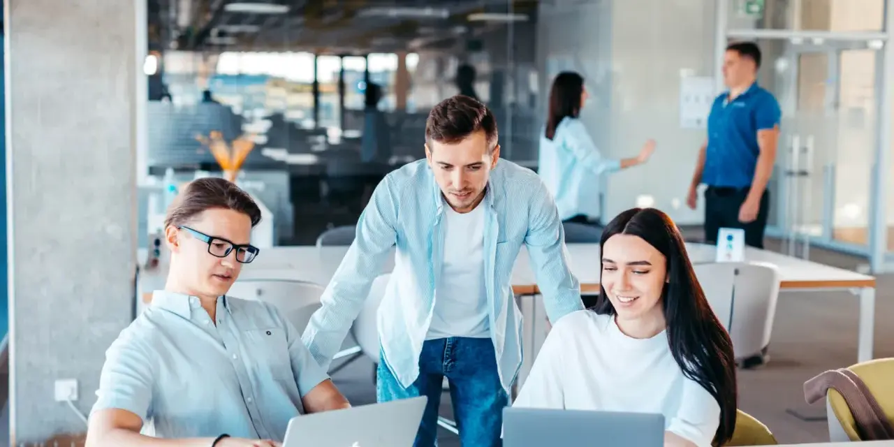 Equipo colabora en un proyecto, usando laptops y aplicaciones informáticas para gestionar la cuenta contable.