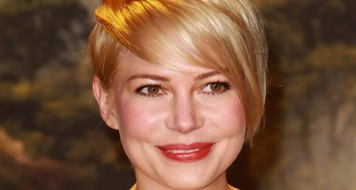 Uśmiechnięta kobieta z okrągłą twarzą i blond fryzurą, z burzą złotych włosów opadających na czoło.