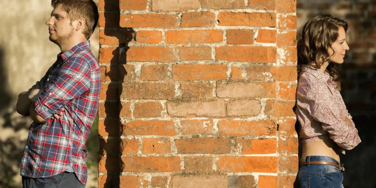 Un homme et une femme se tournent le dos, appuyés contre un mur de briques. Peut-on fixer quelque chose sur un mur mitoyen ?