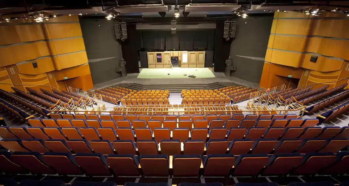Pusta widownia Teatru Muzycznego im. Danuty Baduszkowej. Pomarańczowe fotele czekają na widzów, scena gotowa na spektakl.