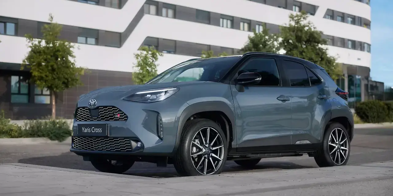 Szary Toyota Yaris Cross hybryda stoi na tle nowoczesnego budynku.