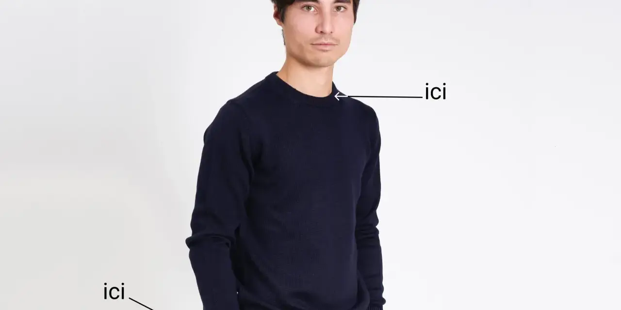 Un homme porte un pull bleu marine. Le tissu pul endroit envers est visible sur le bord du pull.