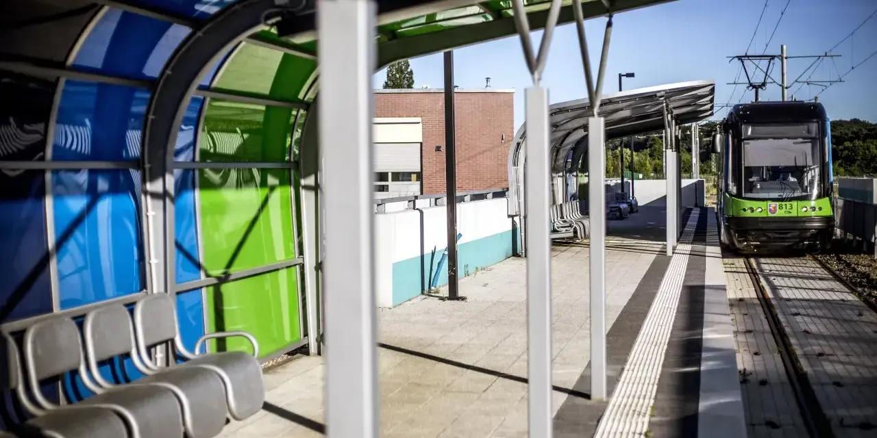 Nowoczesny przystanek tramwajowy w Szczecinie. Zielony tramwaj czeka na pasażerów. Jak dojechać do centrum?