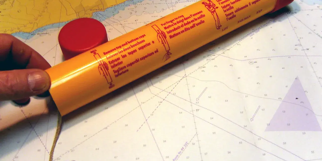 Seenot-Leuchtrakete mit roter Kappe und Anleitung auf einer Seekarte.