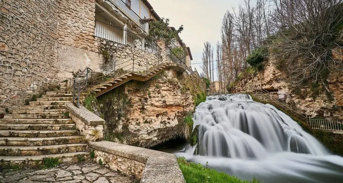 Escaleras de piedra y un caserío se funden con la cascada en la Alcarria Alta.
