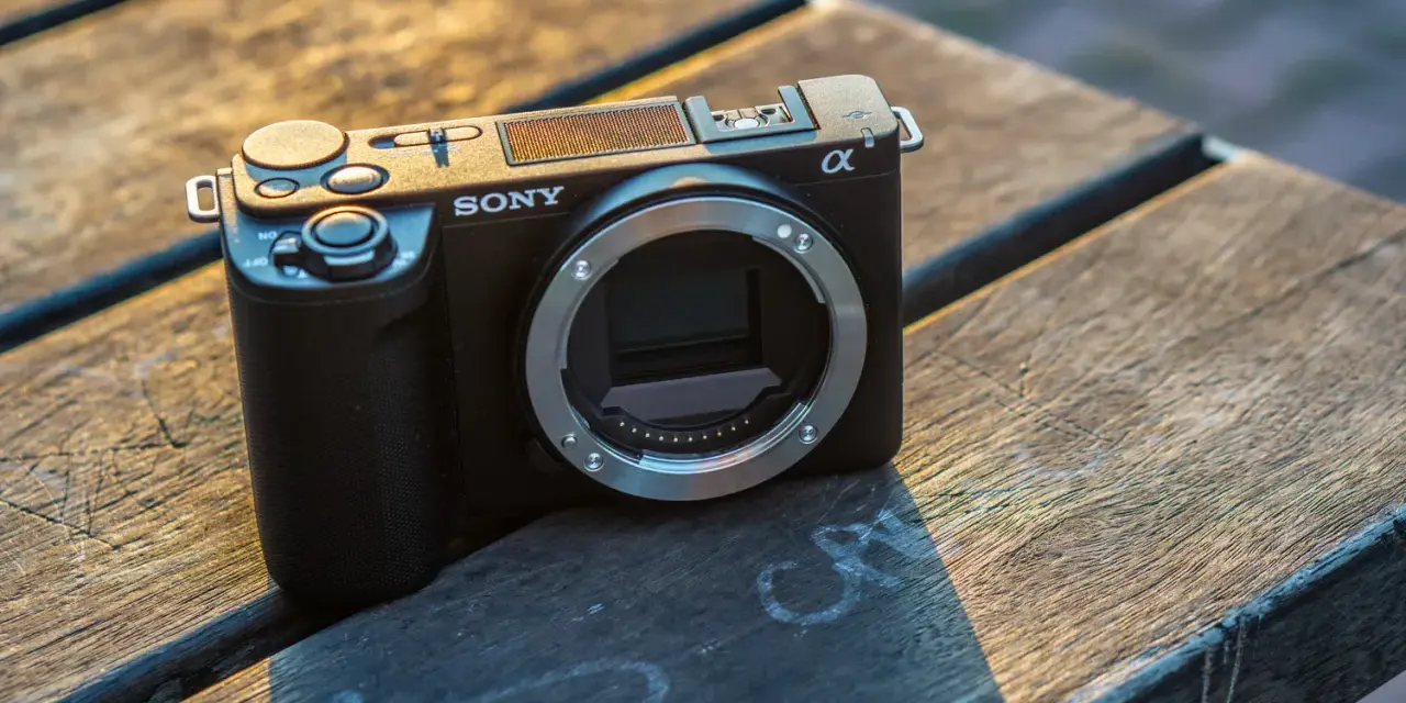 Czarny aparat Sony α6000, model zve10, leży na drewnianym stole.