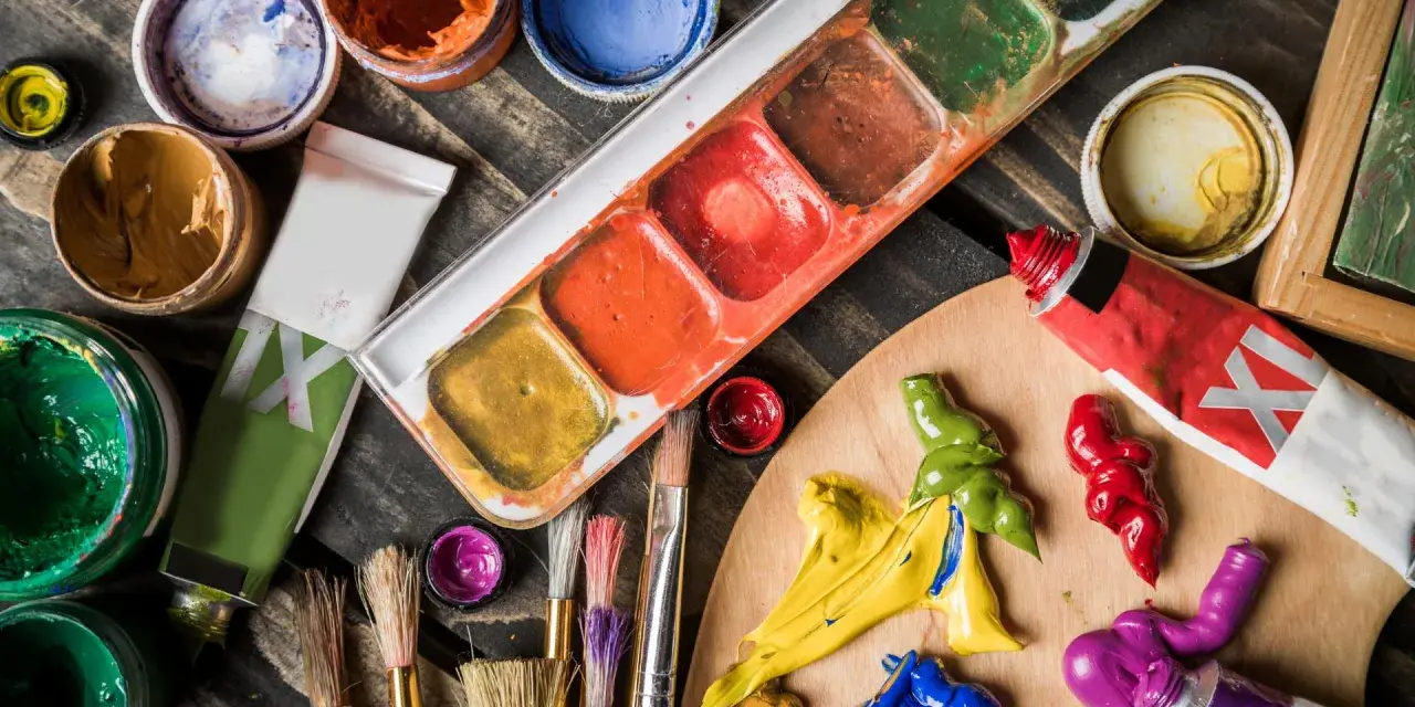 Palette de couleurs vives pour une peinture à l'acrylique. Tubes de peinture, pinceaux et pots de couleurs sont prêts pour la création artistique.
