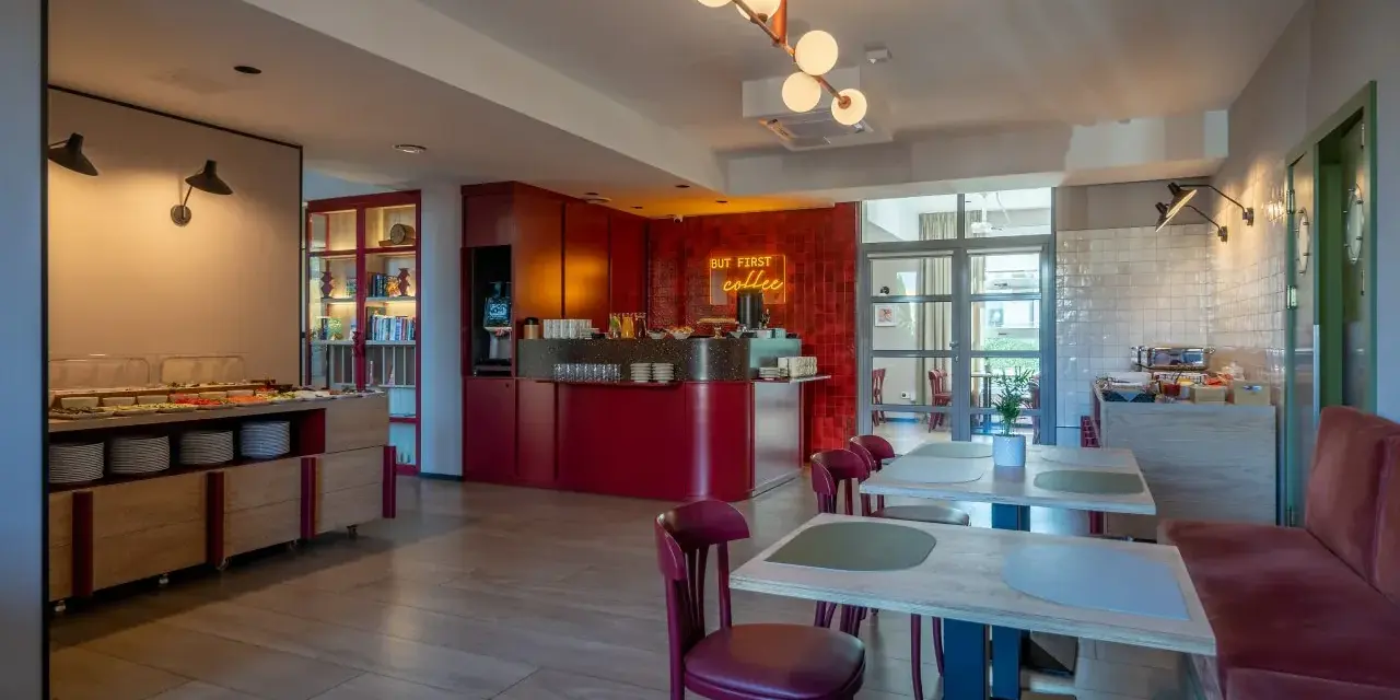 Nowe, stylowe wnętrze z bufetem śniadaniowym i neonem "But first coffee". Idealne miejsce na poranną kawę, zgodnie z licznymi hotel Antares opinie.