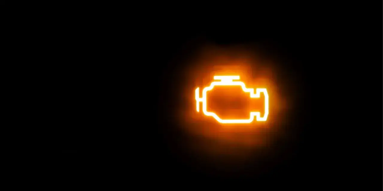 Icona luminosa arancione di un motore su sfondo nero. La spia MIL accesa indica un problema.