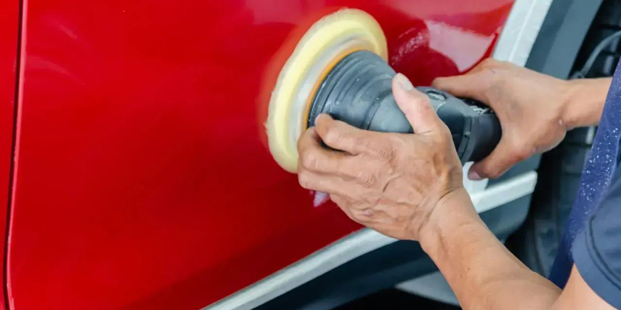 Ręce polerują czerwony lakier auta maszyną polerską. To kluczowy etap, jak woskować auto, by uzyskać lustrzany połysk i ochronę.