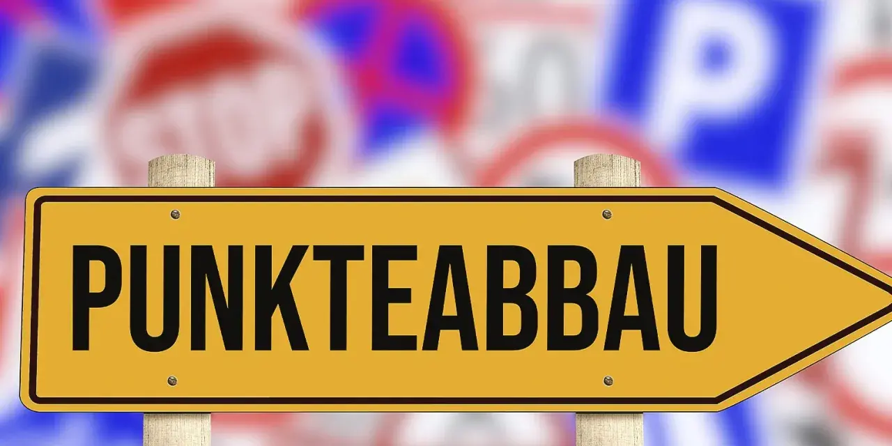Gelbes Schild mit der Aufschrift "PUNKTEABBAU" weist den Weg. Informieren Sie sich über die fahreignungsseminar kosten, um Punkte abzubauen.