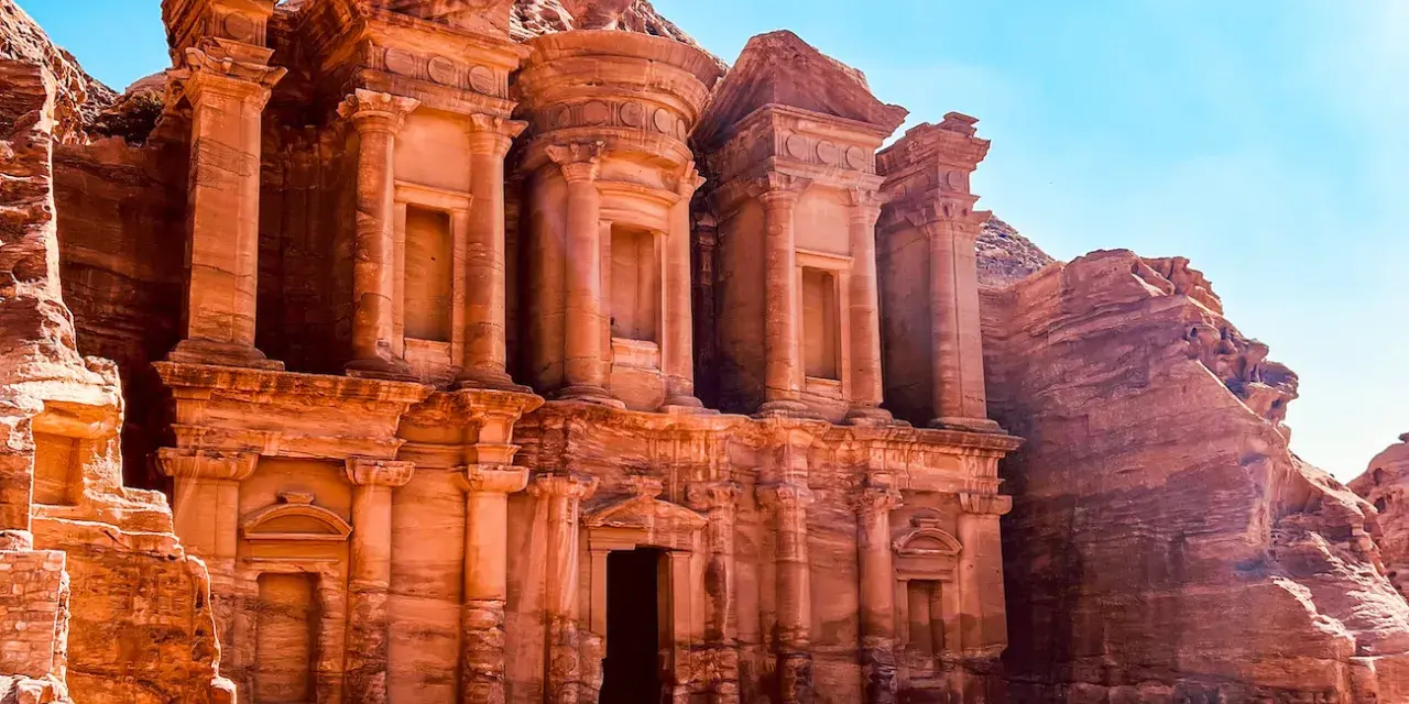 Le Monastère d'Ad-Deir, un trésor de Petra en Jordanie, se dresse majestueusement sculpté dans la roche ocre sous un ciel bleu éclatant.