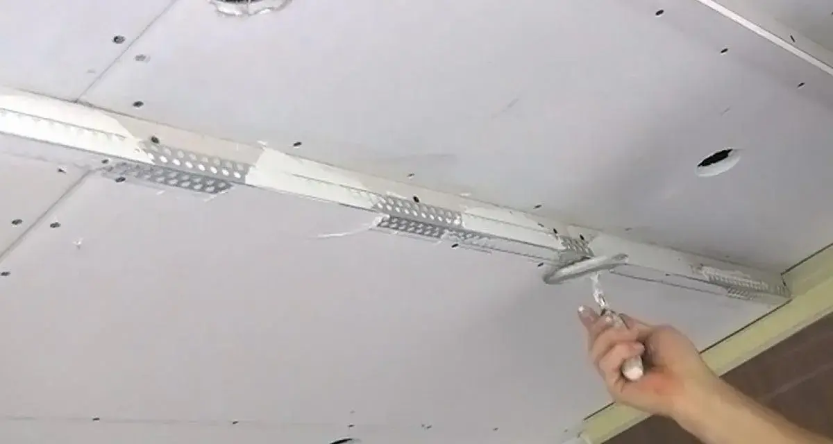 Hand spachtelt Rigipsdecke, um eine glatte Oberfläche für den Innenausbau zu schaffen.