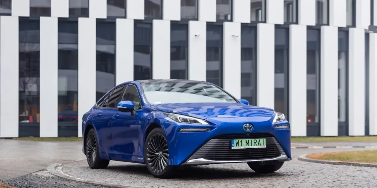 Niebieski samochód Toyota Mirai na tle nowoczesnego budynku.