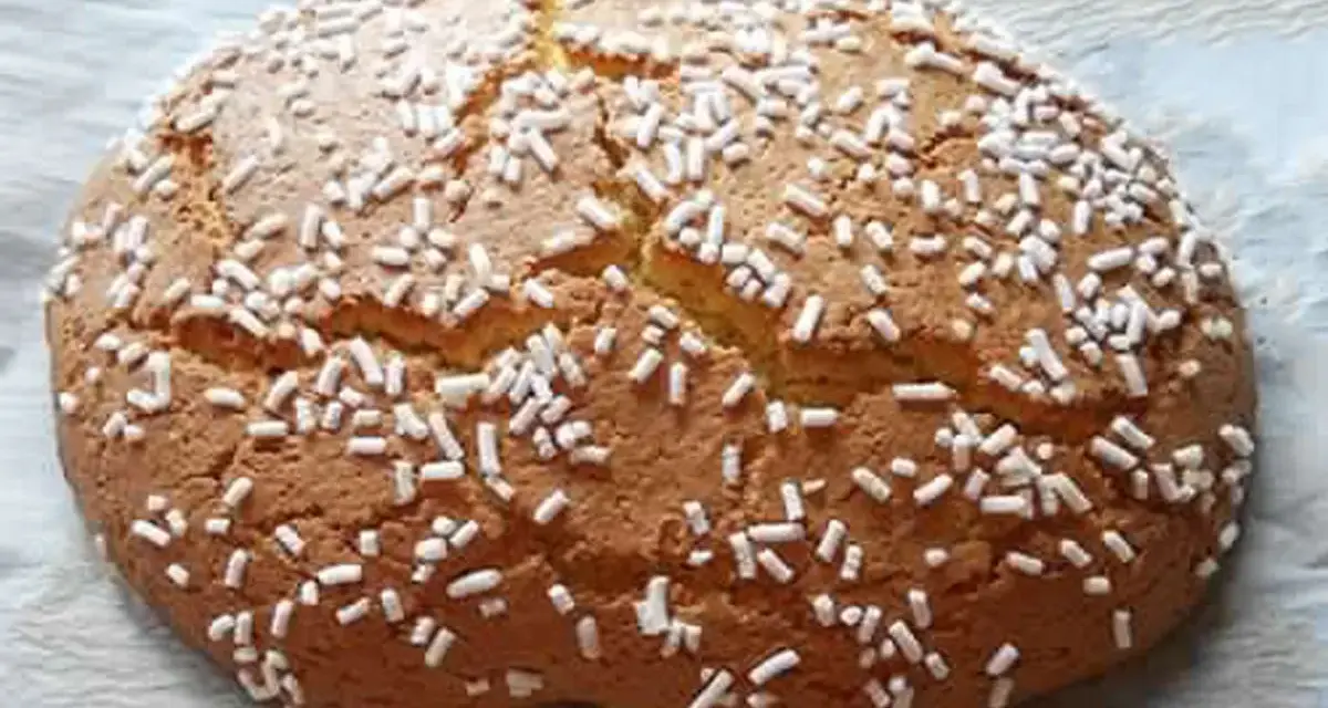 Ciambella romagnola artusi, soffice e dorata, cosparsa di zuccherini bianchi. Un dolce che sa di casa e tradizione.