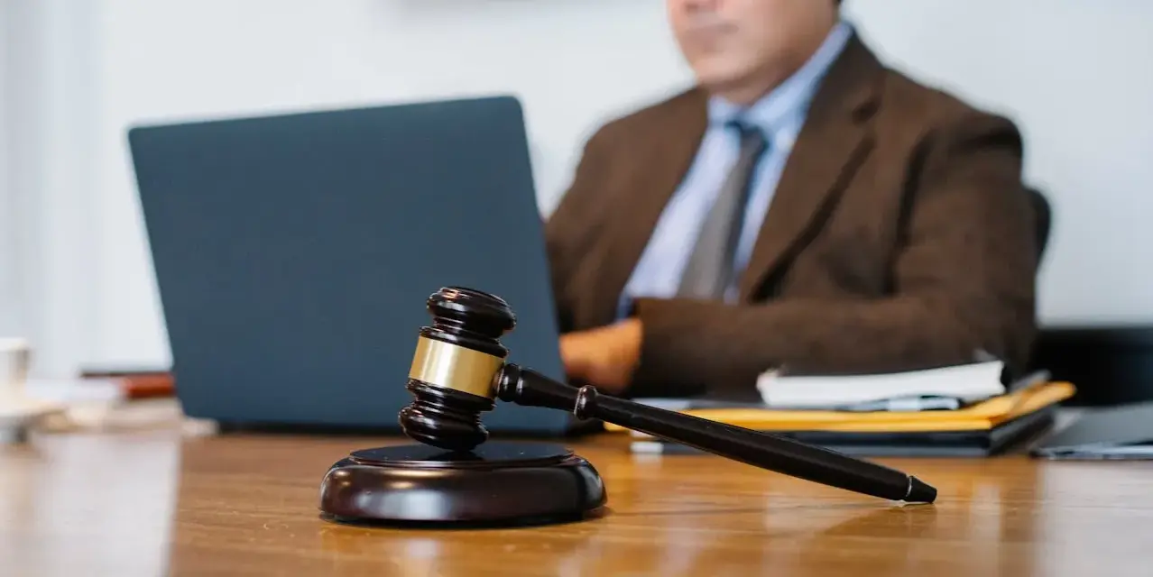 Sądowy młotek na biurku, prawnik pracuje przy laptopie. Dyskrecja w ujawnieniu informacji o zadłużeniu osobom trzecim.
