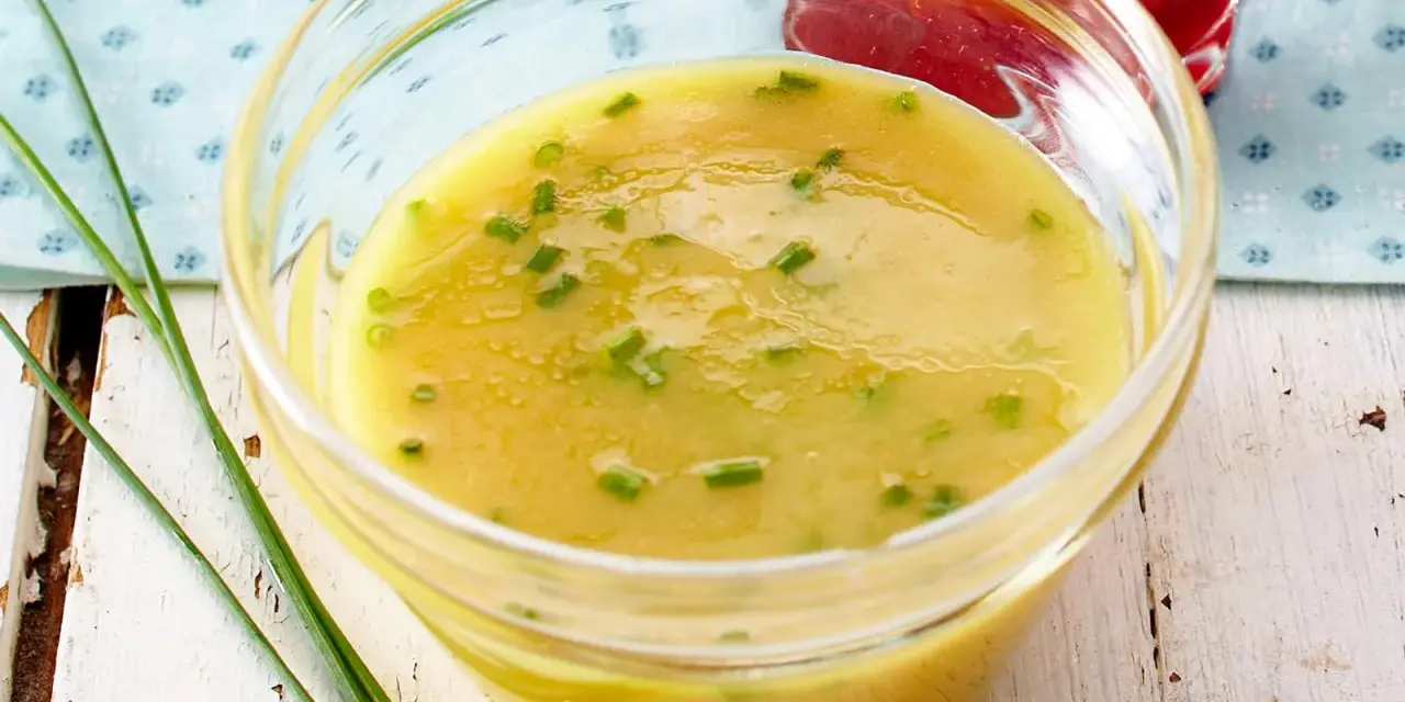 Ein Glas mit cremigem honig senf dressing, garniert mit Schnittlauch. Perfekt für einen frischen Salat.