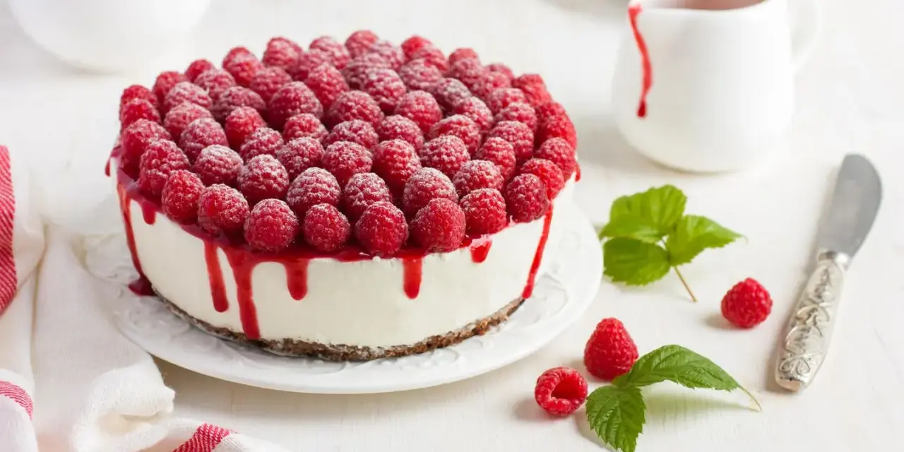 Himbeertorte mit Mascarpone, üppig belegt mit frischen Himbeeren und rotem Fruchtsirup, der über den Rand tropft.