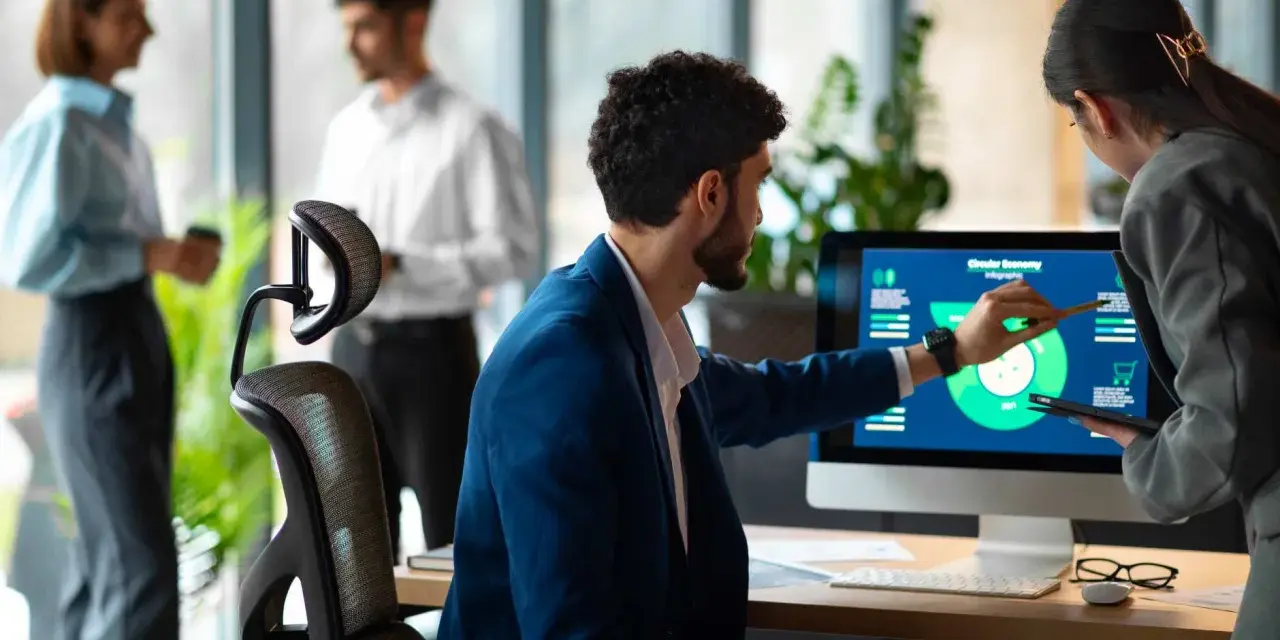 Uomini e donne discutono di grafici su un monitor, esplorando nuove opportunità di lavori del futuro senza laurea.