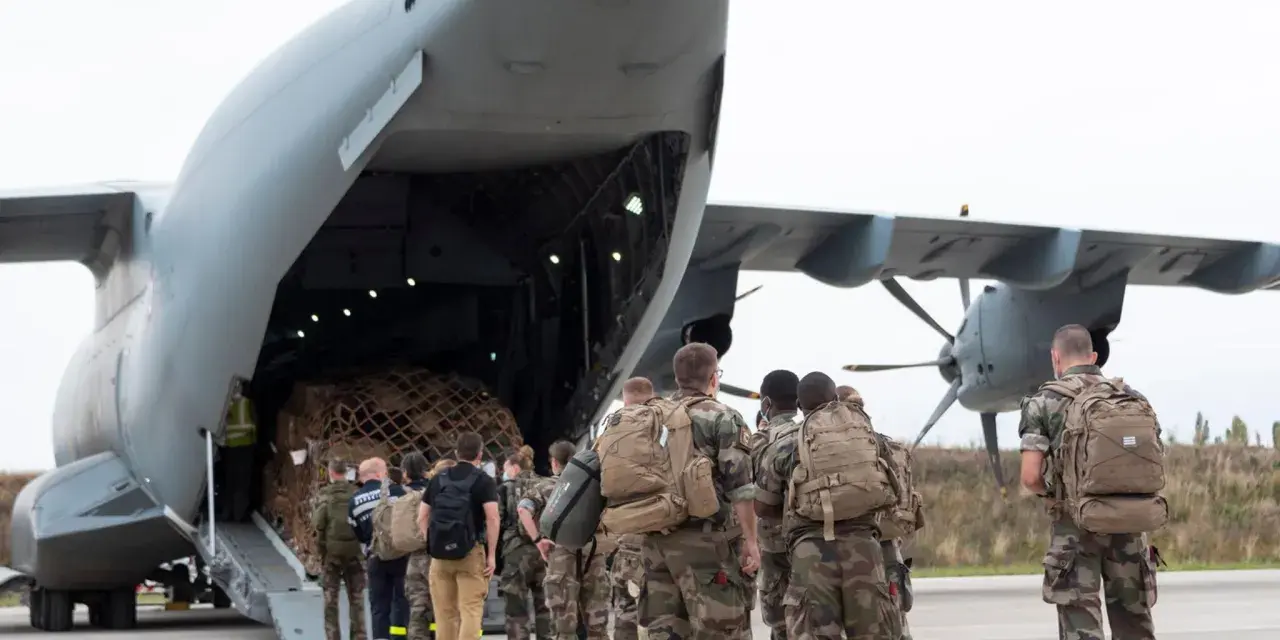 Soldaten mit Rucksäcken stehen vor einem Frachtflugzeug, bereit für ihren Einsatz im Afghanistan-Krieg.