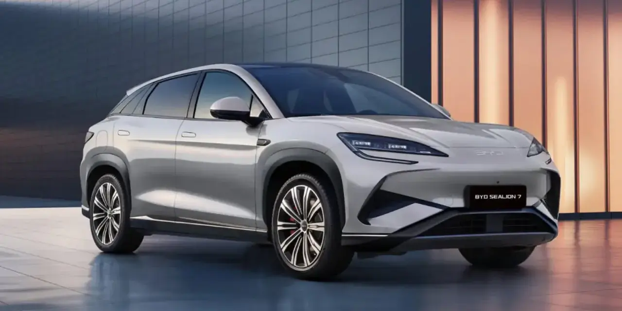 Srebrny SUV BYD Sealion 7 z nowoczesnym designem, zaparkowany przed budynkiem.