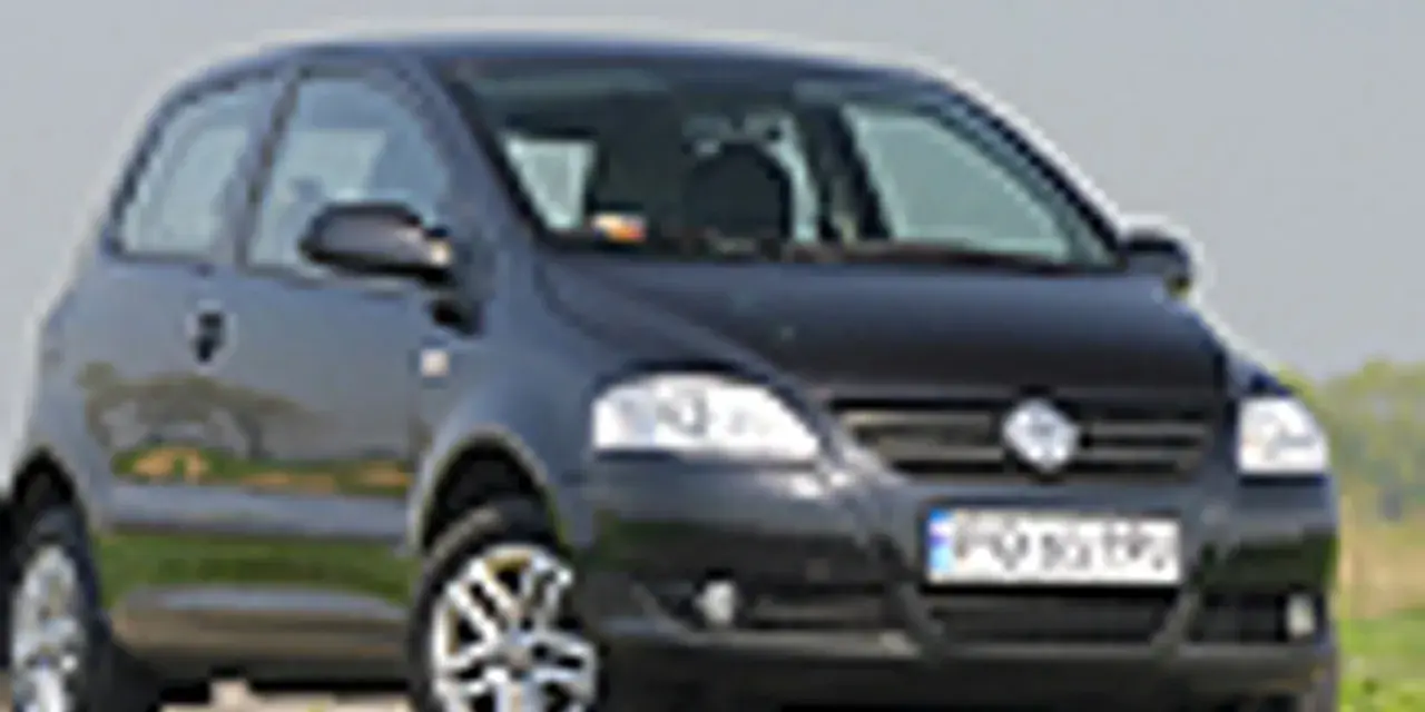 Czarny VW Fox z polskimi tablicami rejestracyjnymi stoi na tle zieleni.