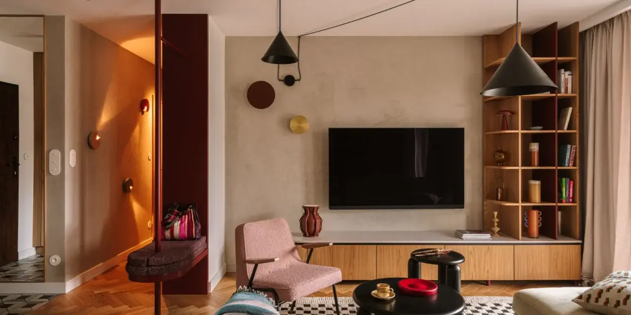 Nowoczesny salon z elementami boho. Wygodna kanapa, różowy fotel, czarne stoliki i regał. W przedpokoju ławka i lustro. Idealne miejsce na relaks po całym dniu. Ten **kosztorys remontu** był wart każdej złotówki.