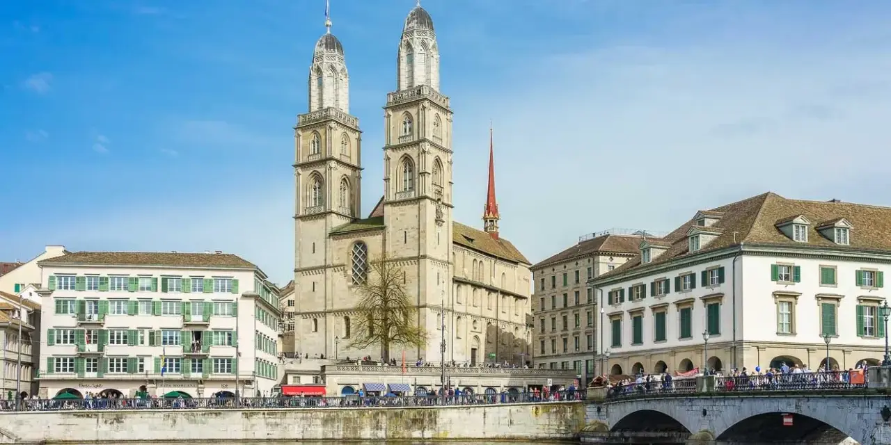 Zurych co warto zobaczyć: imponująca katedra Grossmünster z dwiema wieżami, rzeka Limmat i most.