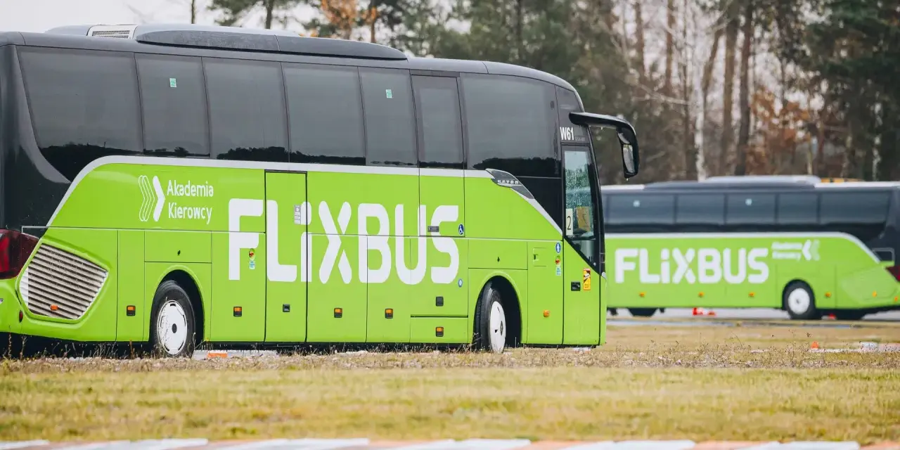 Zielony autobus Flixbus z napisem "Akademia Kierowcy" stoi na trawie. Czyżby kolejne flixbus opóźnienia?