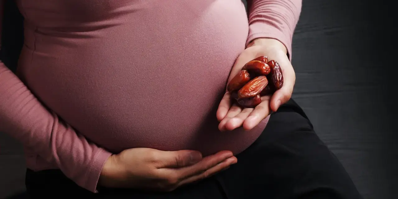 Kobieta w ciąży trzyma w dłoni garść daktyli. To naturalny sposób na wsparcie organizmu w tym wyjątkowym czasie.