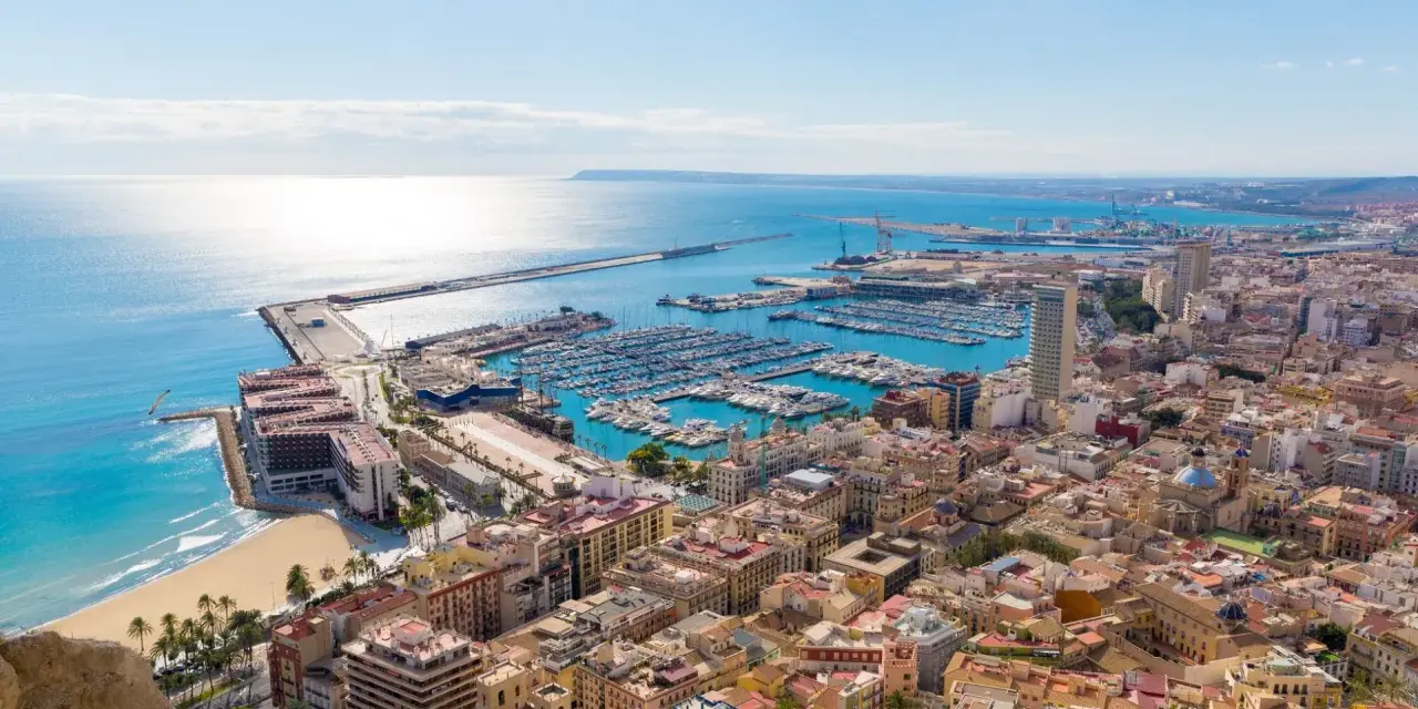 Widok na port jachtowy i plażę w słoneczny dzień. Tak właśnie wygląda Alicante, gdzie jest to piękne miasto.