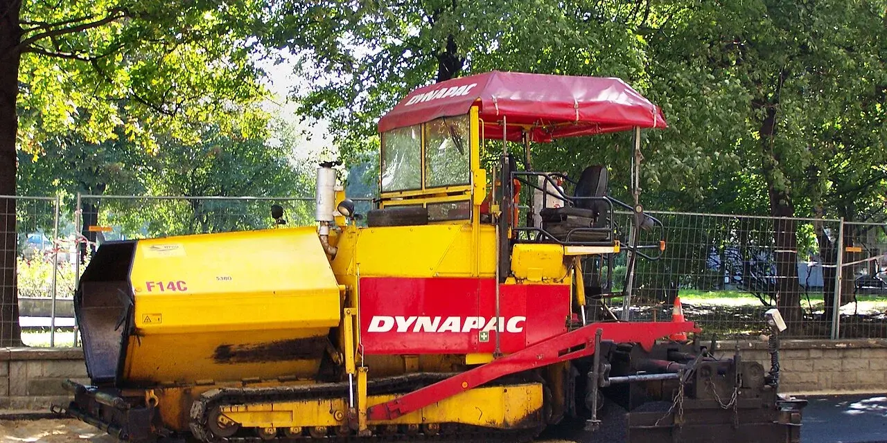 Żółto-czerwony rozściełacz do kruszywa Dynapac F14C na placu budowy.