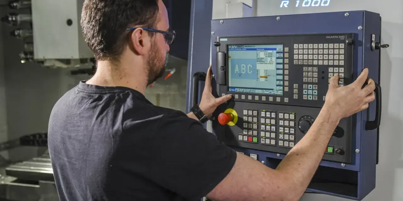 Operator CNC przy panelu sterowania. Dobra praca to wysokie operator cnc zarobki.