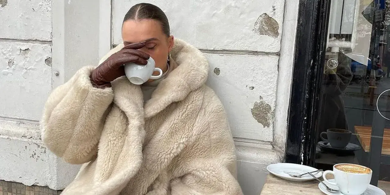 Vanilla girl w kremowym futrze pije kawę, otulona ciepłem i spokojem.