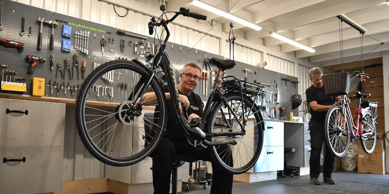 Mekaniker arbetar med en elcykel i verkstad. Verktyg på väggen visar att detta är en plats för bidrag till elcykel.