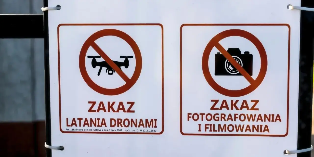 Dwa znaki na płocie: zakaz latania dronami i zakaz fotografowania i filmowania.