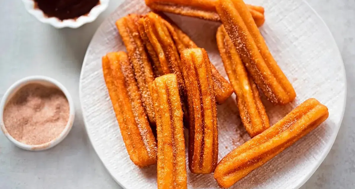 Churros sin gluten espolvoreados con azúcar y canela, servidos con chocolate caliente.