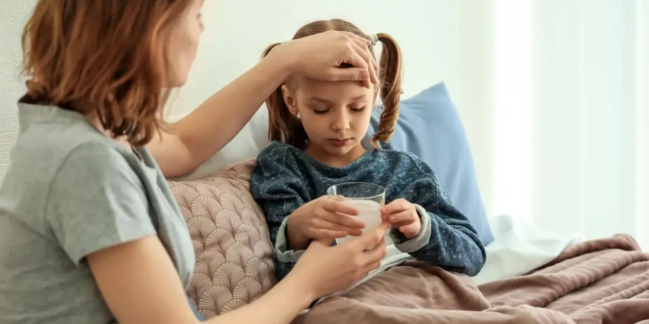 Mutter prüft Fieber bei krankem Kind im Bett. Die Krankschreibung für die Schule ist nötig, damit das Kind sich erholen kann.