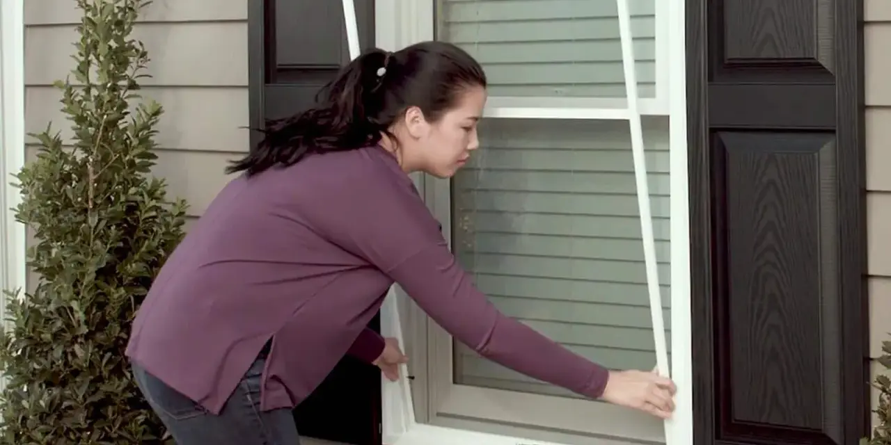 Woman demonstrates how to replace screen door mesh on a window.